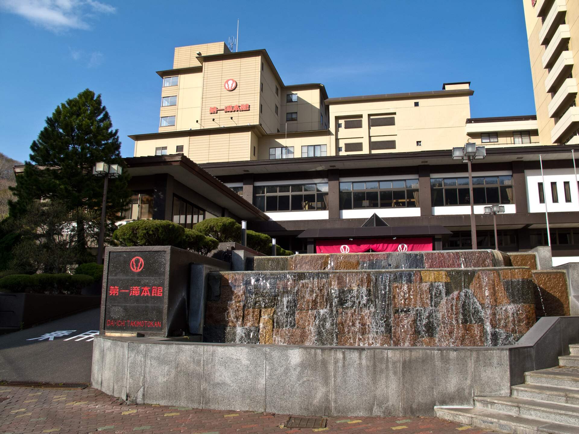 第一滝本館の外観。玄関前に館名の看板と水が流れ落ちる石積み