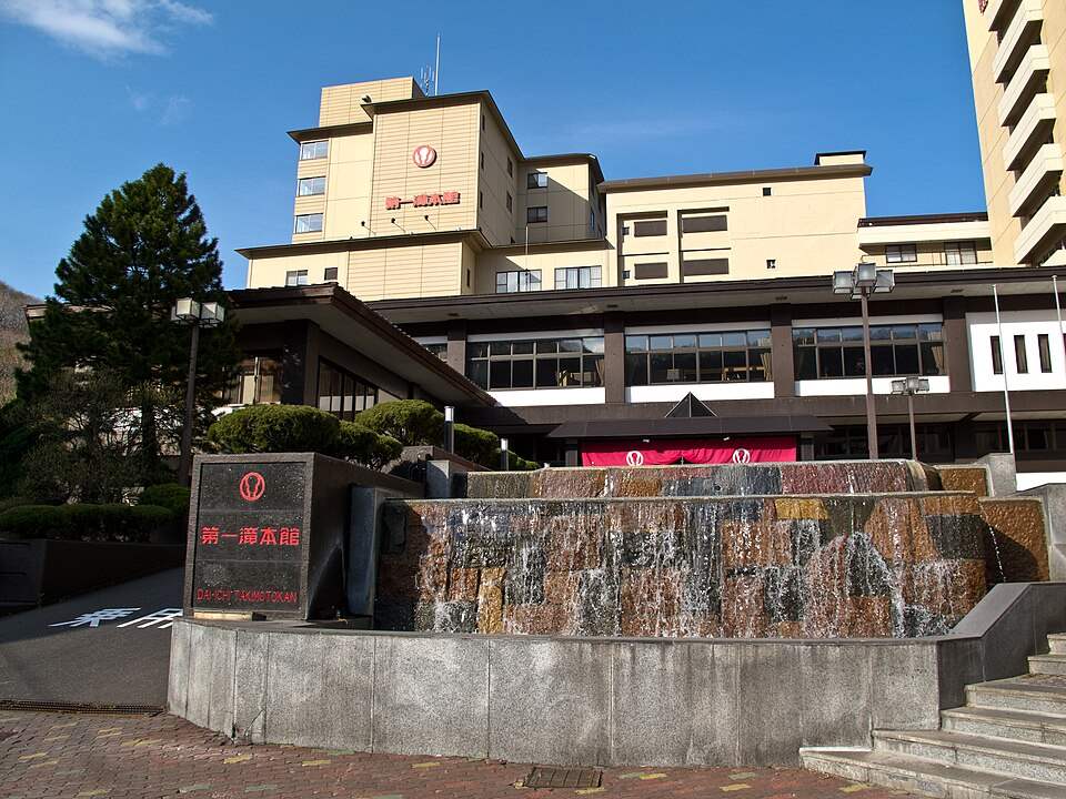 第一滝本館の外観。玄関前に館名の看板と水が流れ落ちる石積み