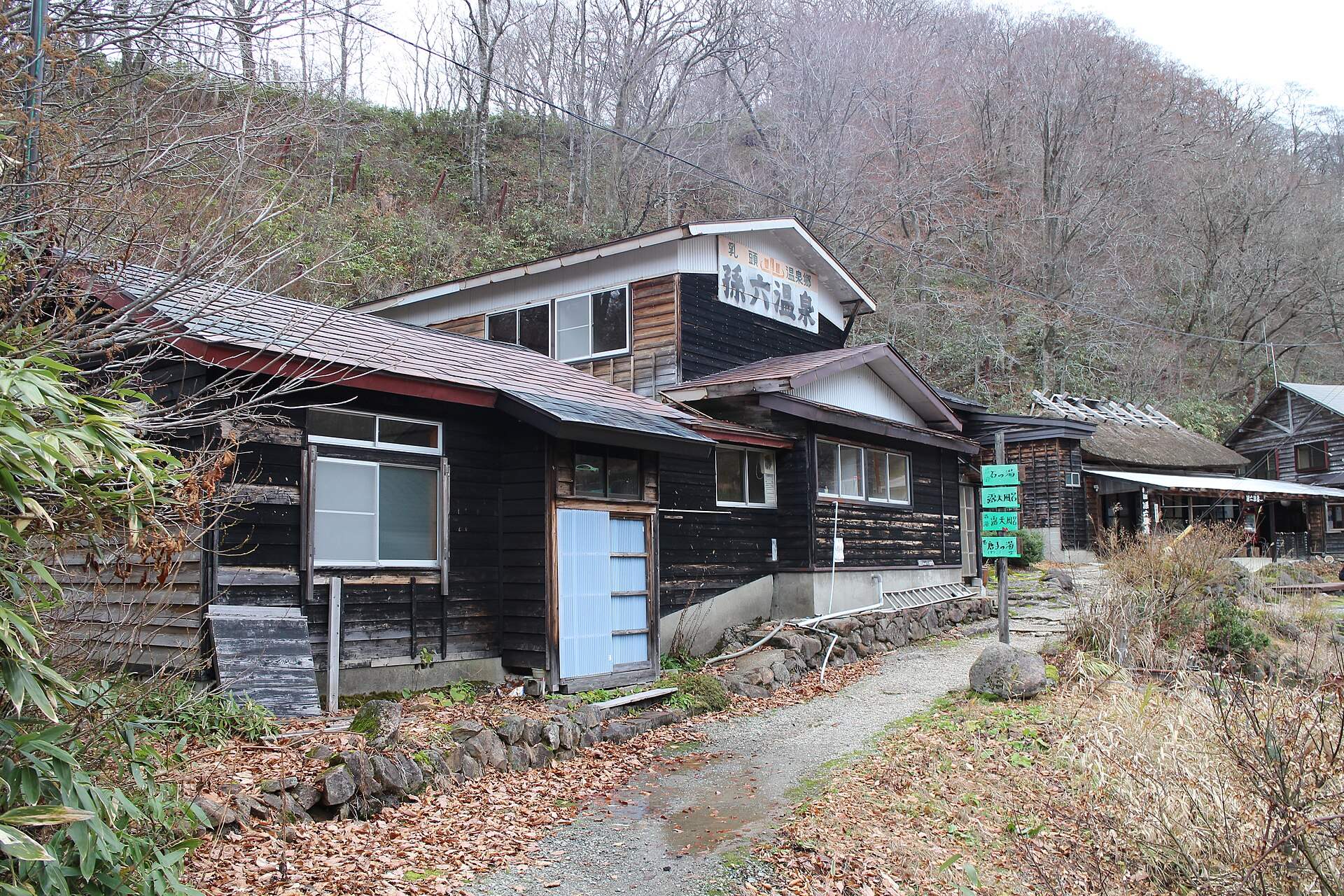 山あいに建つ孫六温泉の木造の湯小屋と宿