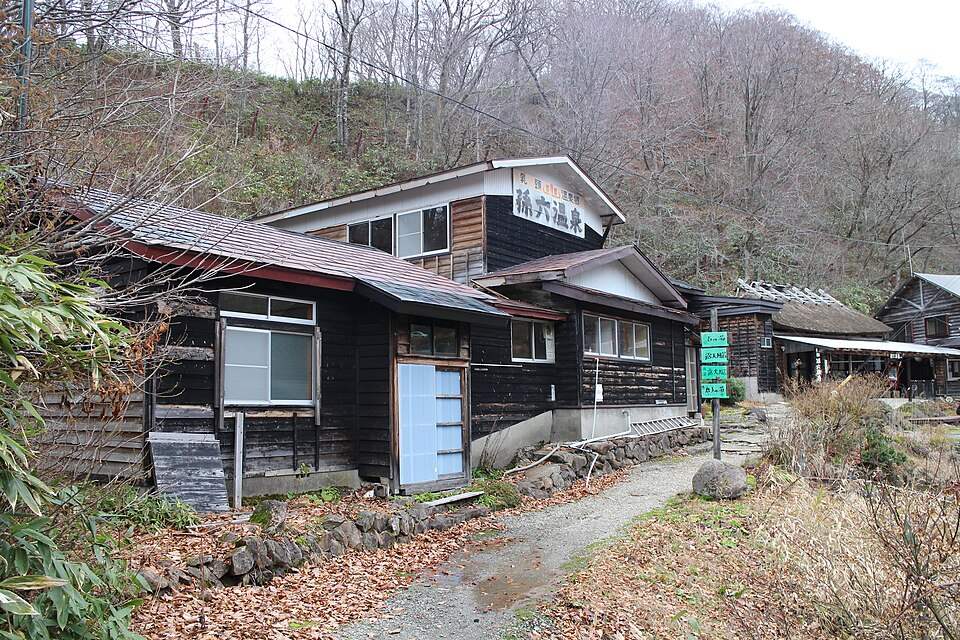 山あいに建つ孫六温泉の木造の湯小屋と宿