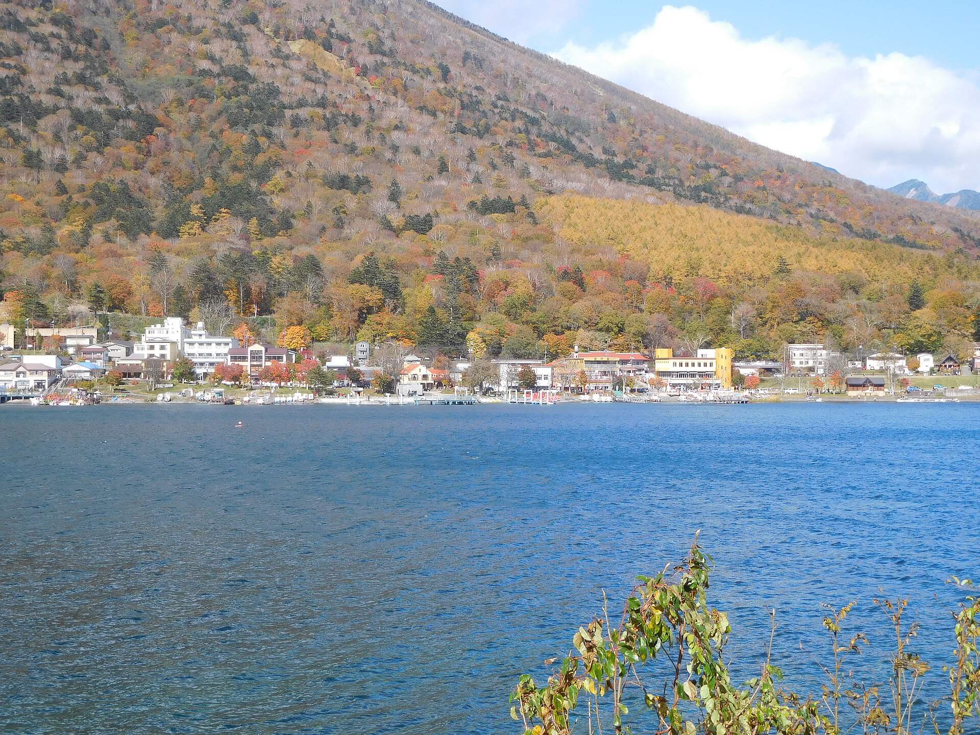 中禅寺湖の対岸から見た、紅葉の山すそに並ぶ中禅寺温泉の街並み