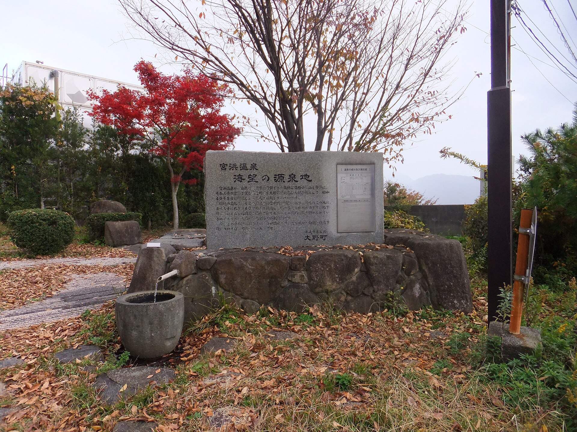 宮浜温泉の「海望の源泉地」の碑と湯の出る石の鉢、紅葉