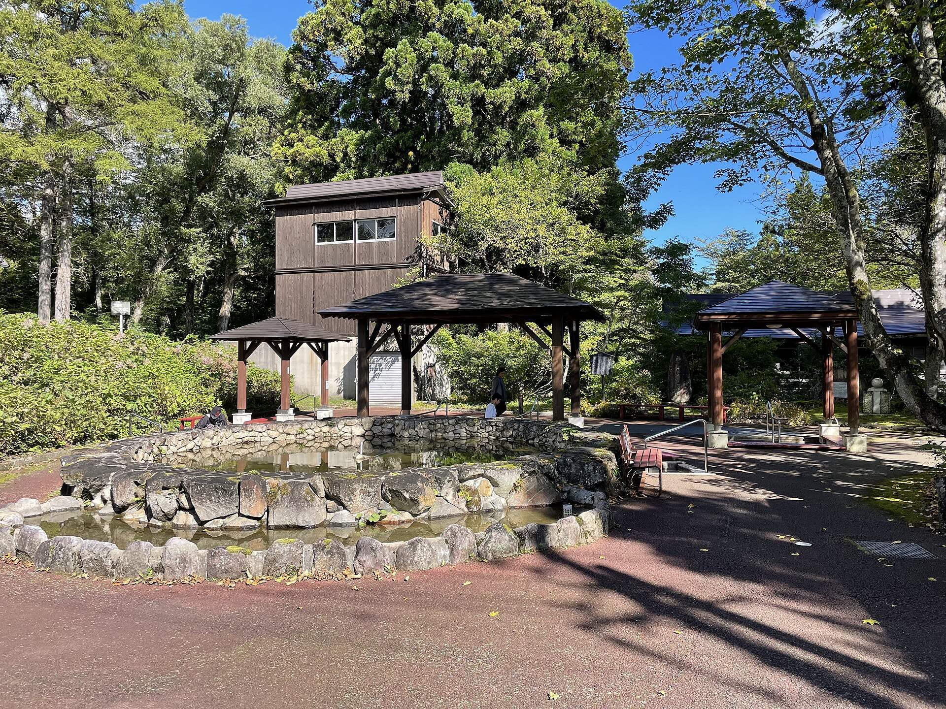 赤倉温泉の足湯公園。木立の中に石造りの足湯とあずまや