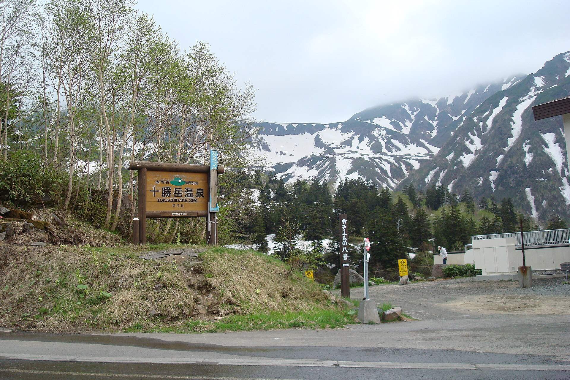 十勝岳温泉の看板と残雪の山並み