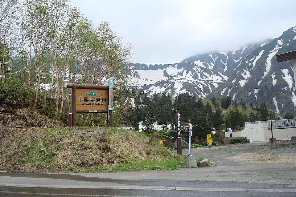 十勝岳温泉の看板と残雪の山並み