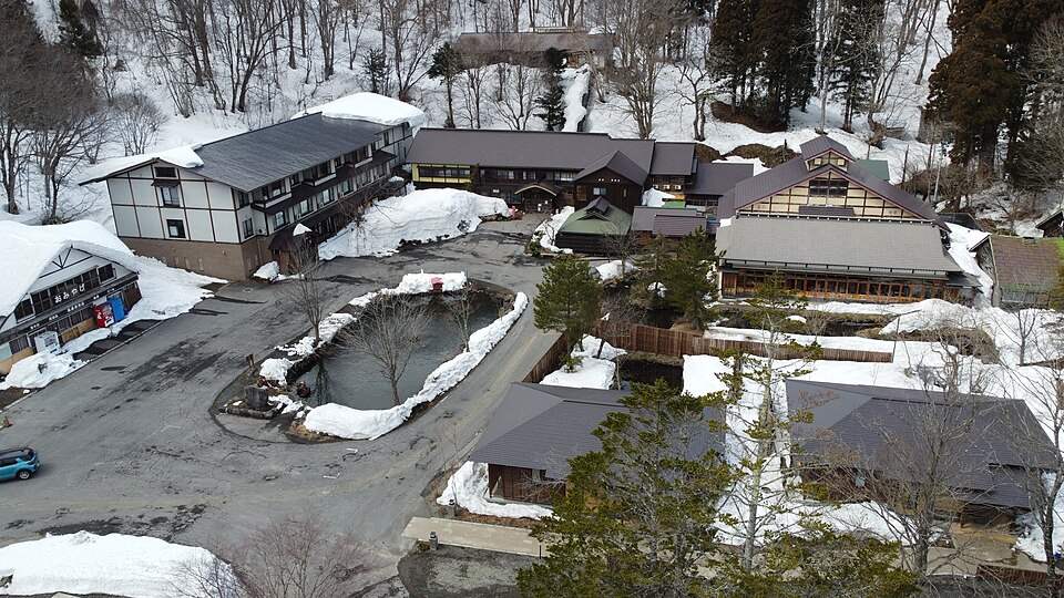 雪の残るブナの森に建つ蔦温泉の旅館(上空から)