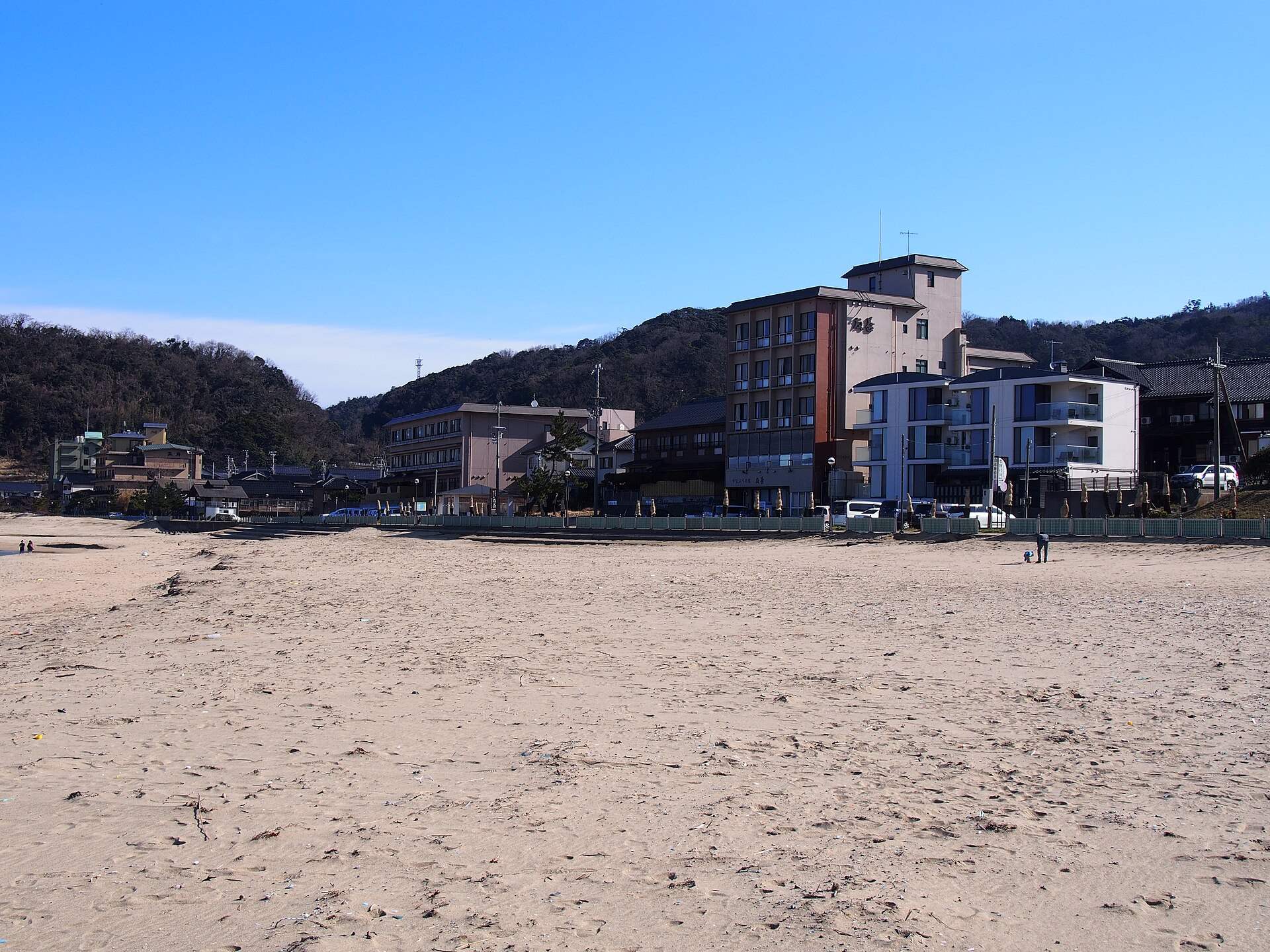 夕日ヶ浦の砂浜と浜沿いに並ぶ夕日ヶ浦温泉の旅館
