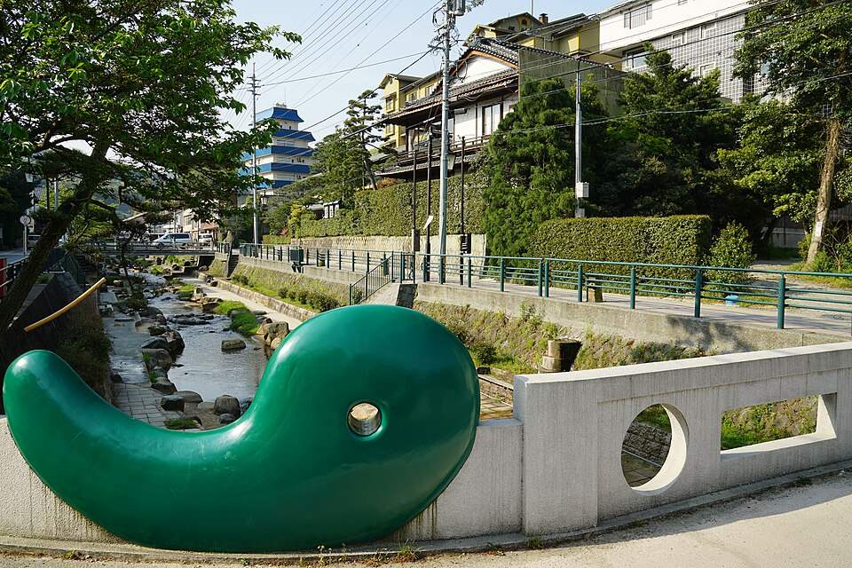 玉湯川沿いの玉造温泉の街並みと、橋のたもとの緑色のオブジェ